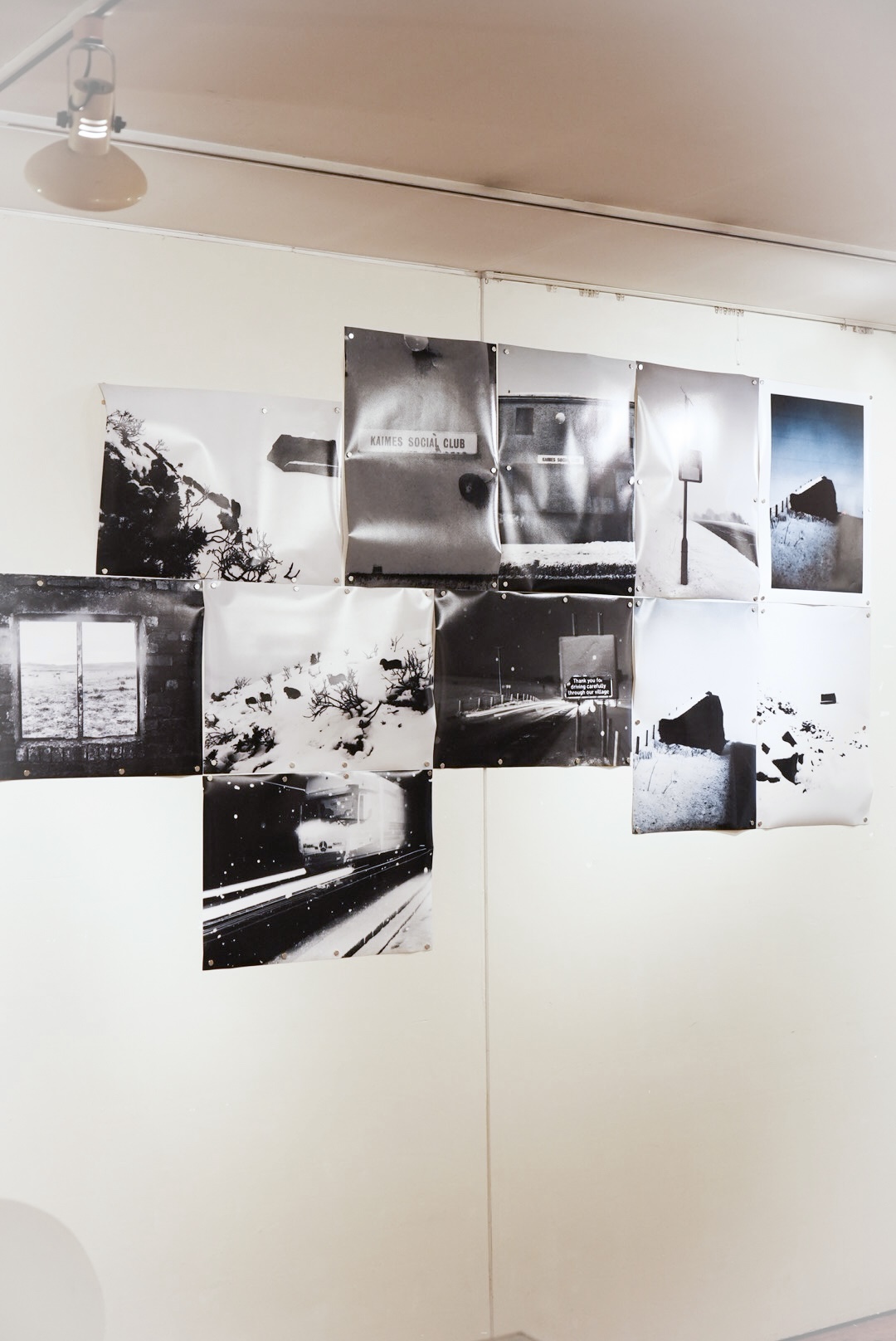 Unframed photographic prints pinned to the gallery wall